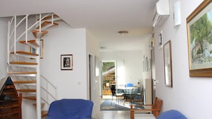 A spacious living area with a staircase, two blue armchairs, a dining table with chairs, and a view of a garden through an open door. - Beautiful Apartment With Sea View, Trogir, Croatia (Trogir)