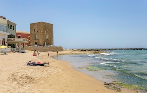 A beach with a stone tower, sandy beach, and a rocky breakwater. - Stunning home in Chiaramonte Gulfi (Chiaramonte Gulfi)