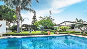 Ein Swimmingpool, umgeben von gepflegten Gärten und einer Vielfalt an Bäumen.