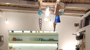 Een eethoek met een houten tafel gedekt voor vier personen, witte stoelen en een keuken op de achtergrond.