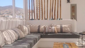 Een moderne woonkamer met een bank, kussens, een salontafel en uitzicht op een bergachtig landschap door een raam.