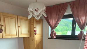 Un dormitorio pequeño y acogedor con una cama individual, un armario de madera y una ventana con cortinas a cuadros.