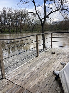 A wooden deck with metal railings overlooking a river. - Morels on the Wabash offers Clamping in a Authentic 20 ft Tee Pee - 30x30 deck . (Logansport)