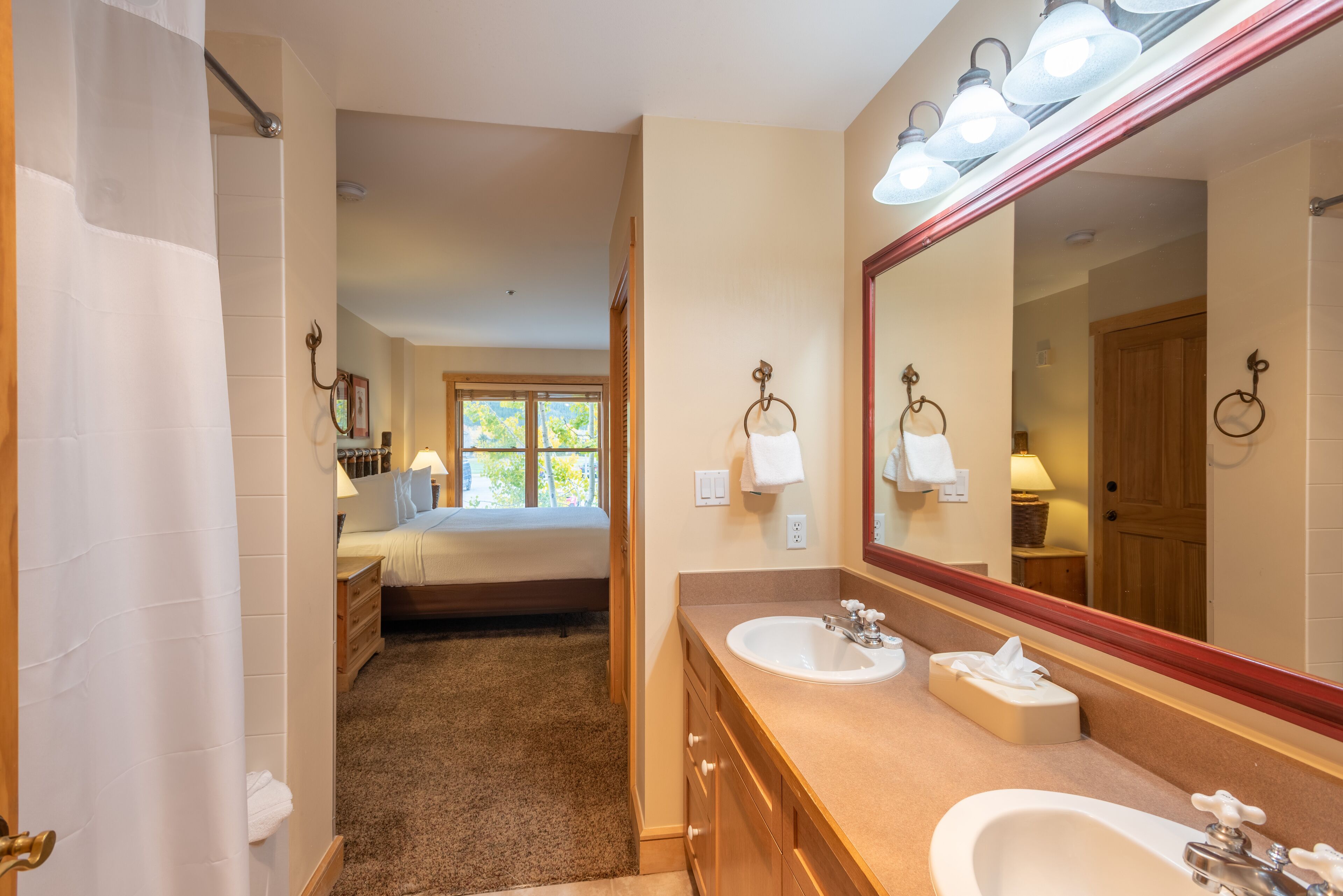 Une salle de bain avec deux lavabos, un grand miroir et une douche.