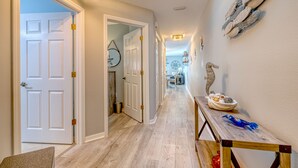 Ein Flur mit Oberlicht, weißen Türen, einer Holzbank mit Dekoration und einer Wand mit Fischmotiven.