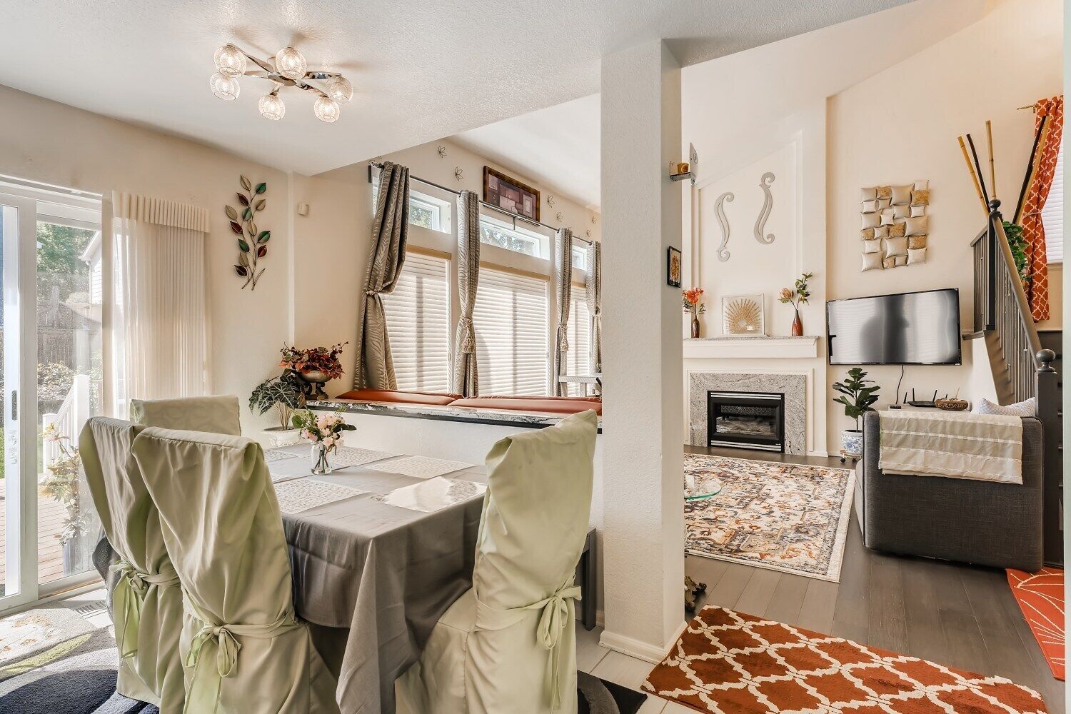 Un comedor con una mesa lista para cuatro personas, una chimenea y un televisor montado en la pared.
