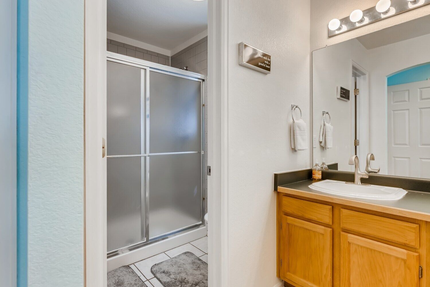 A bathroom with a shower, vanity, and mirror.