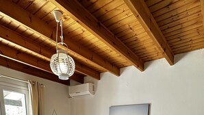 Een slaapkamer met een groot bed, houten vloeren, een plafondventilator en uitzicht op de omgeving.