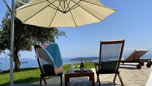 Een terras met twee stoelen, een tafel en een parasol met uitzicht op een prachtig landschap.