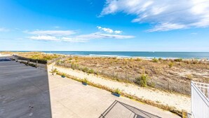 A beachfront property with a concrete patio, sandy beach, and a wooden fence.