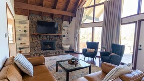 A cozy living room with a stone fireplace, leather sofas, and a television.