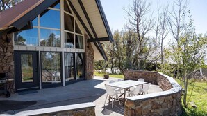 A modern house with a stone exterior, large windows, and a patio with outdoor furniture. - Quiet, Overlook Golf Course, Close to Town, Shopping and Dining (Pagosa Springs)