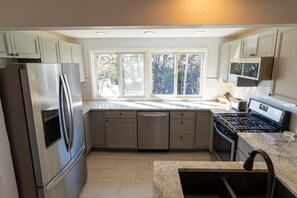 Cocina moderna con electrodomésticos de acero inoxidable, lavavajillas y ventana que proporciona luz natural.