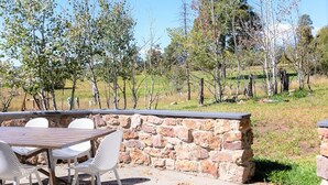 An outdoor patio with a stone wall, a wooden table, and white chairs. - Quiet, Overlook Golf Course, Close to Town, Shopping and Dining (Pagosa Springs)