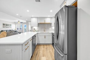 Una cocina moderna con armarios blancos, un refrigerador de acero inoxidable y piso de madera.