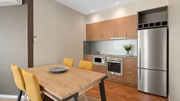 A modern kitchen with wooden cabinets, a stainless steel refrigerator, a microwave, and an oven.