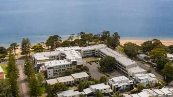 A coastal residential area with modern buildings, a parking lot, and a beach in the background.