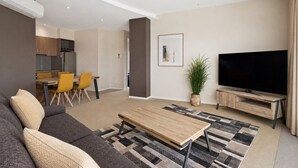 Ein modernes Wohnzimmer mit einer Couch, einem Couchtisch, einem Fernseher und einem Essbereich mit Stühlen.