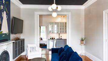 A living room with a dark ceiling, a blue sectional sofa, a white armchair, and a fireplace.