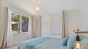 A bedroom with a bed, a window with curtains, a ladder, and a hanging light fixture. - Seaesta Rye by Ready Set Stay - Pet-friendly, solar heated pool, WIFI, Netflix (Rye)