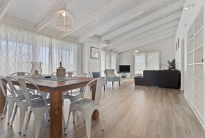 Relax in this inviting living area with a high ceiling, wooden dining table, and comfortable sofa.