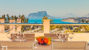Mesa lista para comer con vistas a un pueblo costero y montañas.