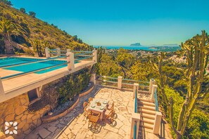 Ein Pool mit einer Steindekke, einem Tisch mit Stühlen und Blick auf die Landschaft.