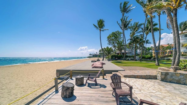 A wooden deck with a table and chairs overlooking a beach.