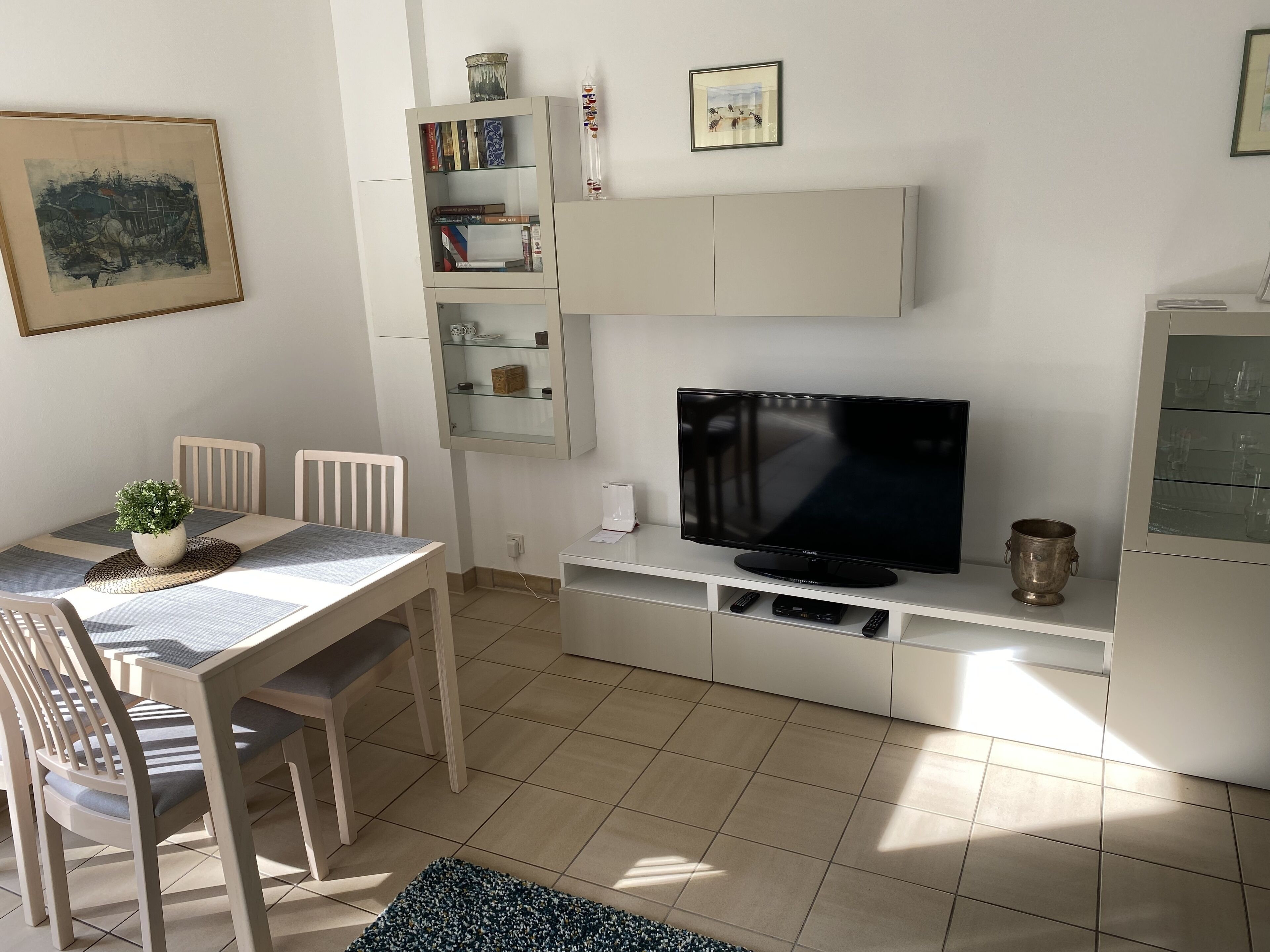 A modern living room with a dining table, chairs, a TV, and a bookshelf.
