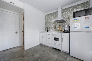 A kitchen with white cabinetry, a microwave, a stove, and a refrigerator.