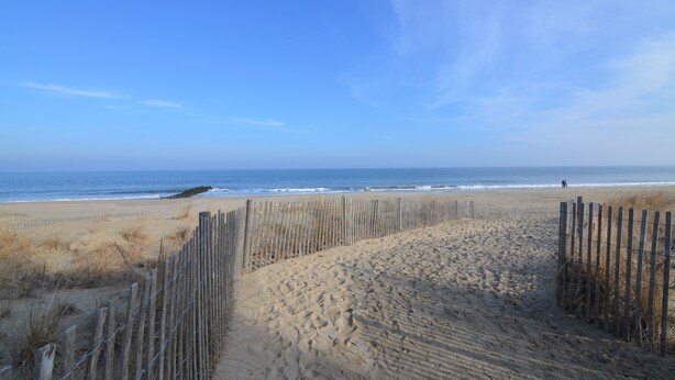 A sandy beach with a wooden fence and a clear blue sky. - ADORABLE STUDIO-OCEAN BLOCK REHOBOTH BEACH, 29 Maryland Ave, Unit 211 (Rehoboth Beach)