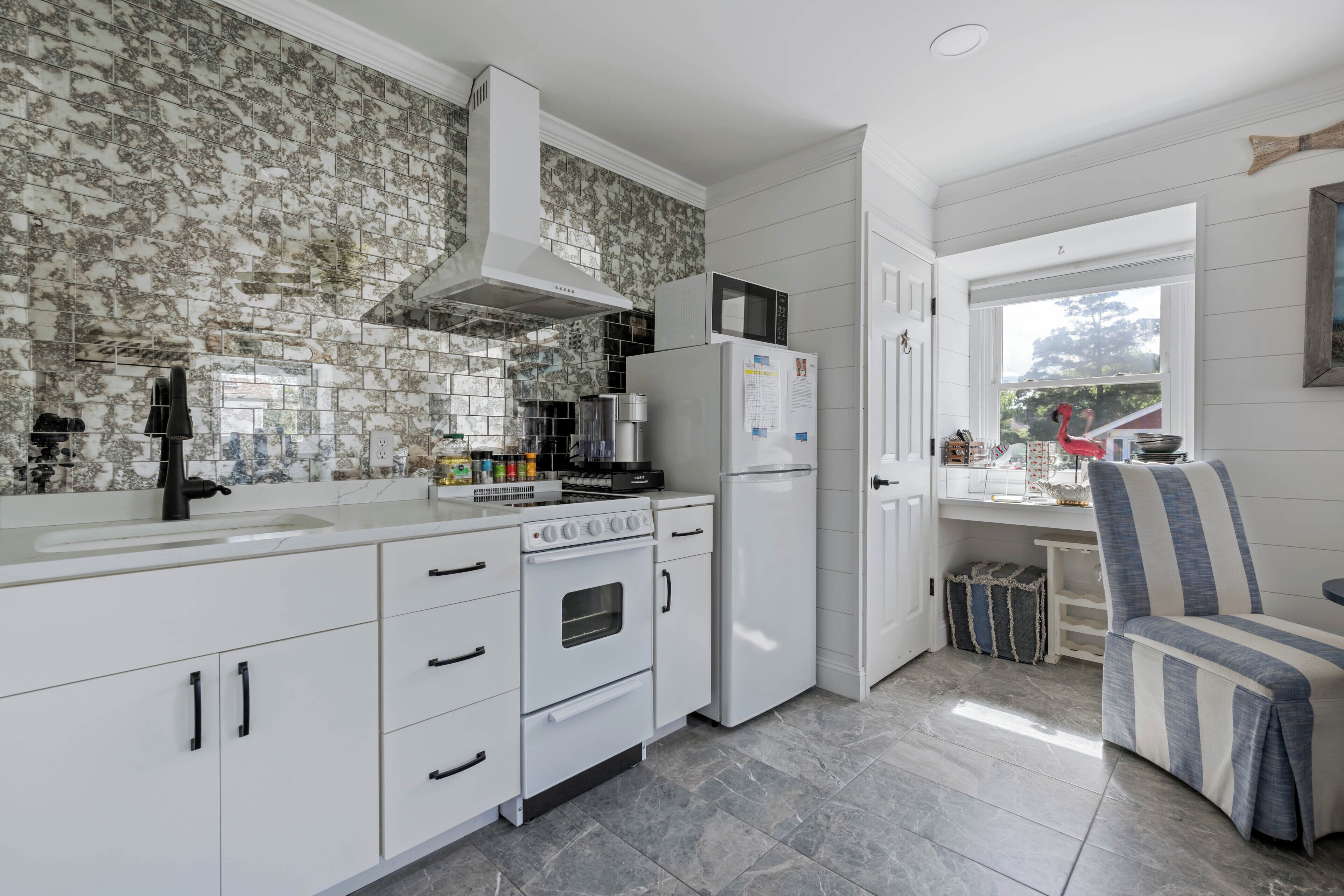 A modern kitchen with white cabinetry, a built-in microwave, and a refrigerator.