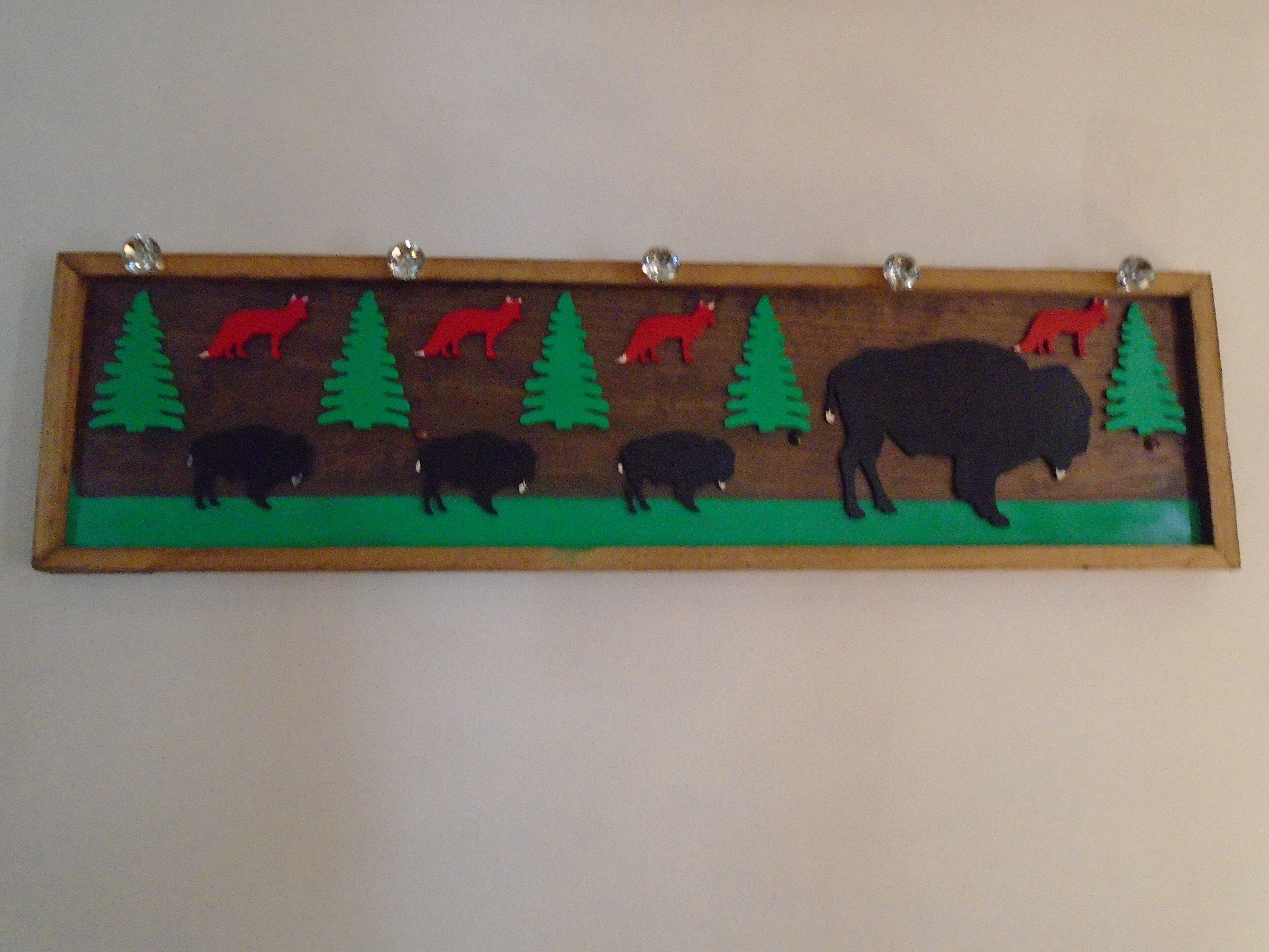 A wooden plaque with animal silhouettes and trees.