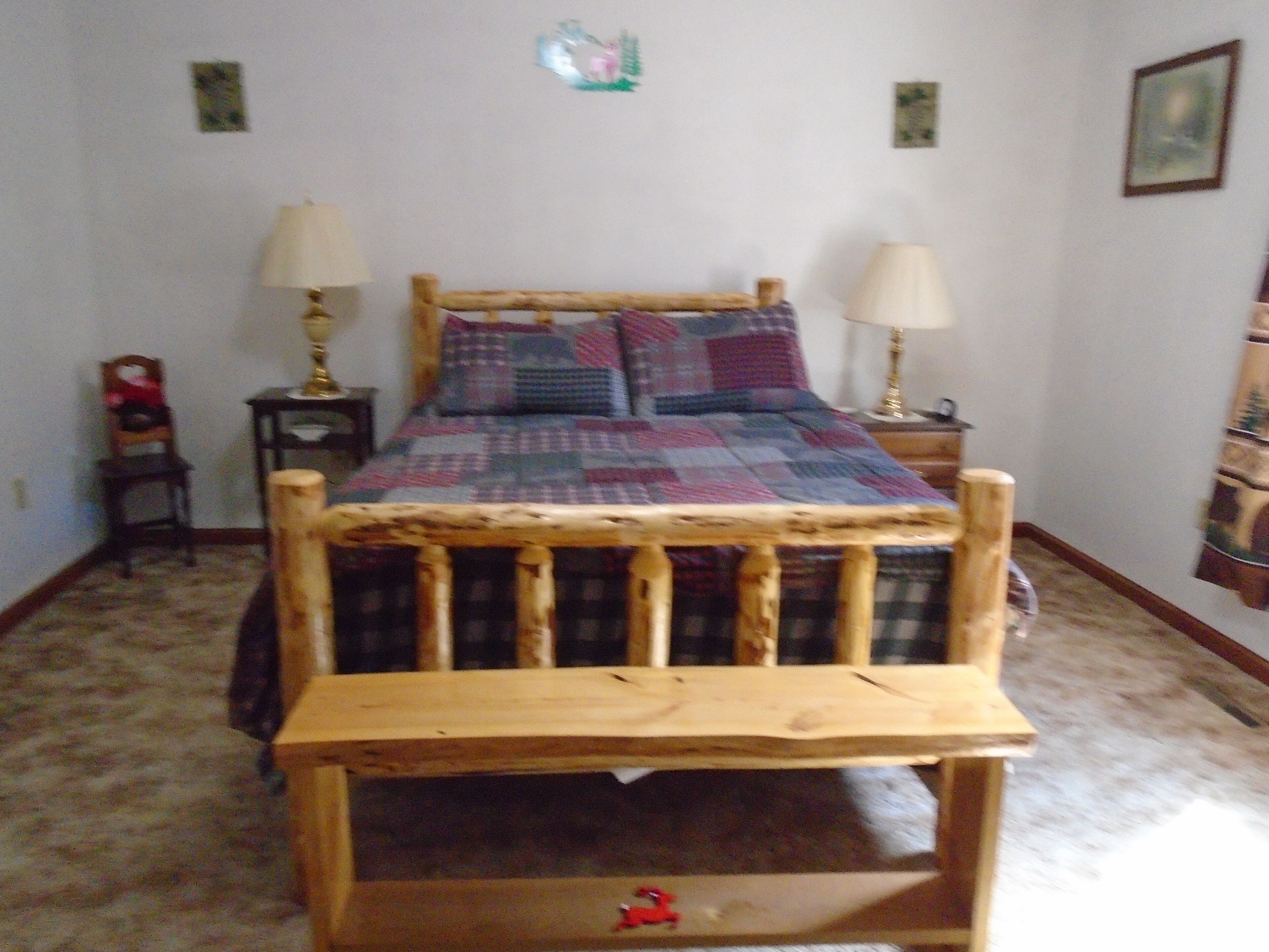 Una cama con cabecera de madera, dos lámparas de noche y un edredón acolchado.