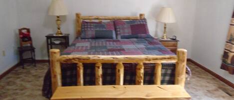 Una cama con cabecera de madera, dos lámparas de noche y un edredón acolchado.