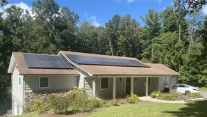 A house with solar panels on the roof, a covered porch, and a car parked in the driveway. - Rustic, Modern Apt - 12 min to DT Asheville  (Weaverville)