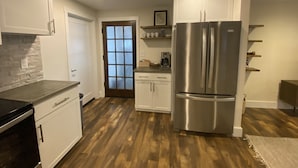 A modern kitchen with white cabinets, a stainless steel refrigerator, and a wooden floor. - Rustic, Modern Apt - 12 min to DT Asheville  (Weaverville)