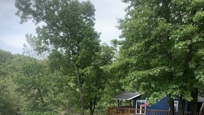 Un chalet au bord du lac, doté d’une terrasse et de meubles d’extérieur, entouré d’arbres et agrémenté d’un quai.