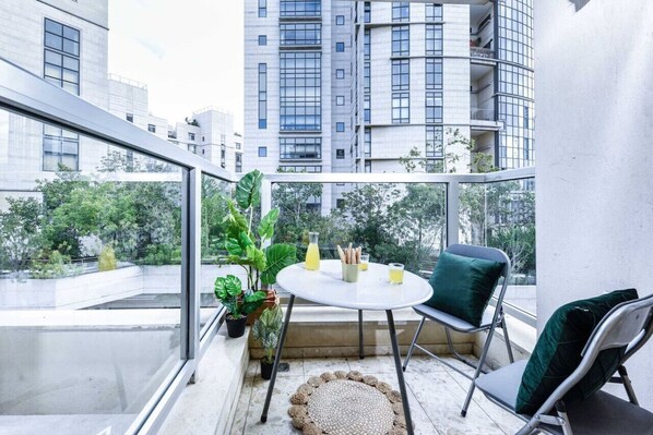 Un balcon avec une table, des chaises et des plantes en pot.