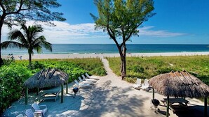A beach pathway leading to beach chairs and thatched umbrellas, with a clear view of the ocean. - Breathtaking Views - Romantic Honeymoon Suite - Jensen's "On the Gulf" 4 (Captiva)