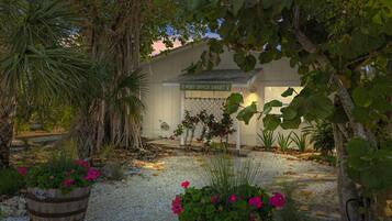 A post office with a sign reading "POST OFFICE SWEET" surrounded by lush greenery and flowering plants.