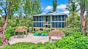 A two-story building with a balcony, surrounded by lush greenery and palm trees. - Breathtaking Views - Romantic Honeymoon Suite - Jensen's "On the Gulf" 4 (Captiva)