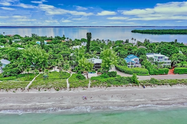 An aerial view of a coastal resort with beachfront properties, lush greenery, and a calm sea.