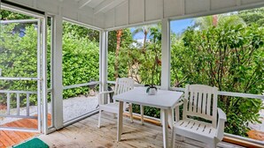 Un espace extérieur abrité, aménagé avec une table et des chaises, et entouré d’une végétation luxuriante.