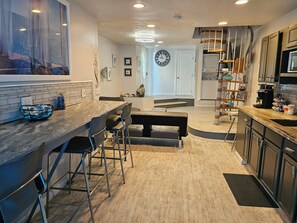 A modern kitchen with a dining area, wooden flooring, and a clock on the wall. - Beautiful San Diego Views, Private Deck, Pool,  Sleeps 9 (Spring Valley)