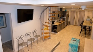 A compact living space with a kitchen, dining area, and a staircase leading to a loft. - Beach Vibes (Spring Valley)
