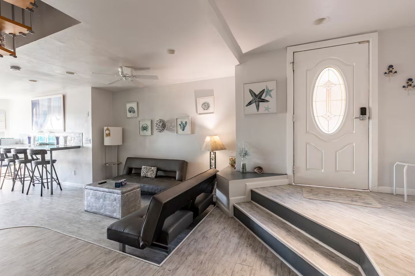 A modern living room with a sofa, a coffee table, and a dining area with bar stools.