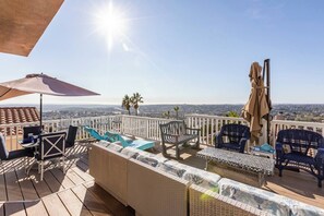 Una terraza en la azotea con mobiliario exterior, vistas a la ciudad y cielo despejado.
