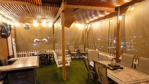 An indoor dining area with tables and chairs, a white picket fence, and a view of the city lights through a large window. - Beach Vibes (Spring Valley)