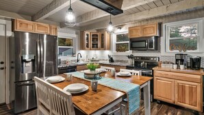 A modern kitchen with wooden cabinets, stainless steel appliances, and a central island with seating.